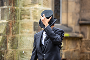 Anand tipping his hat at a funeral in Leeds